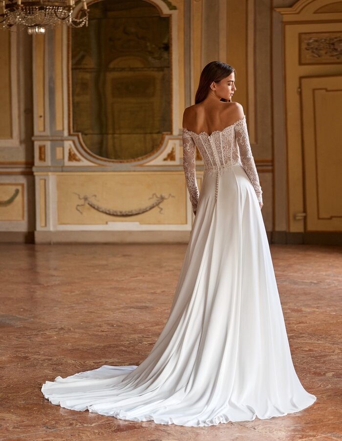 Das Brautkleid Sammi von Alberto Palatchi Brautkleid Sammi von Alberto Palatchi mit romantischem Off-Shoulder-Corsagenoberteil aus Spitze, langen transparenten Spitzenärmeln, betonter Taille und fließendem A-Linien-Rock mit Schleppe