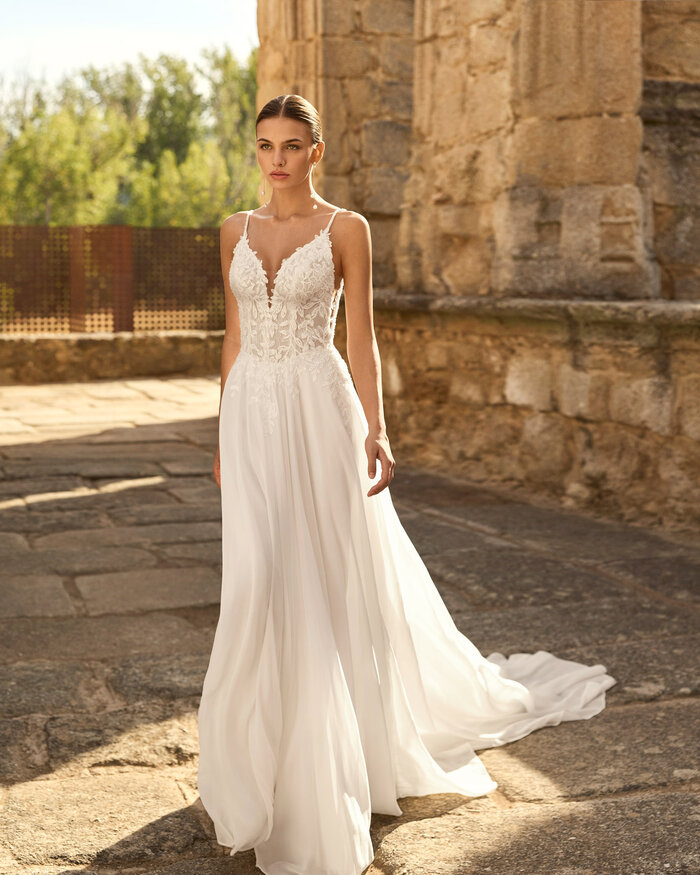 Das Brautkleid Papiro von Adriana Alier Brautkleid Papiro von Adriana Alier mit floraler Spitze, tiefem V-Ausschnitt, feinen Trägern und fließendem Rock mit Schleppe