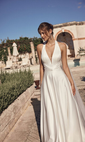 Das Brautkleid Milora D von Modeca Elegantes Brautkleid „Milora D“ von Modeca mit tiefem V-Ausschnitt, Neckholder, schmaler Taille und fließendem Rock