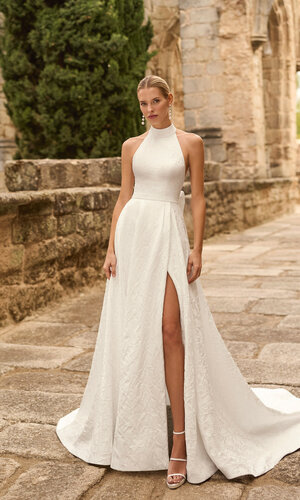 Das Brautkleid Prado von Adriana Alier Brautkleid Prado von Adriana Alier mit elegantem Neckholder-Ausschnitt, floraler Jacquard-Struktur und hohem Beinschlitz