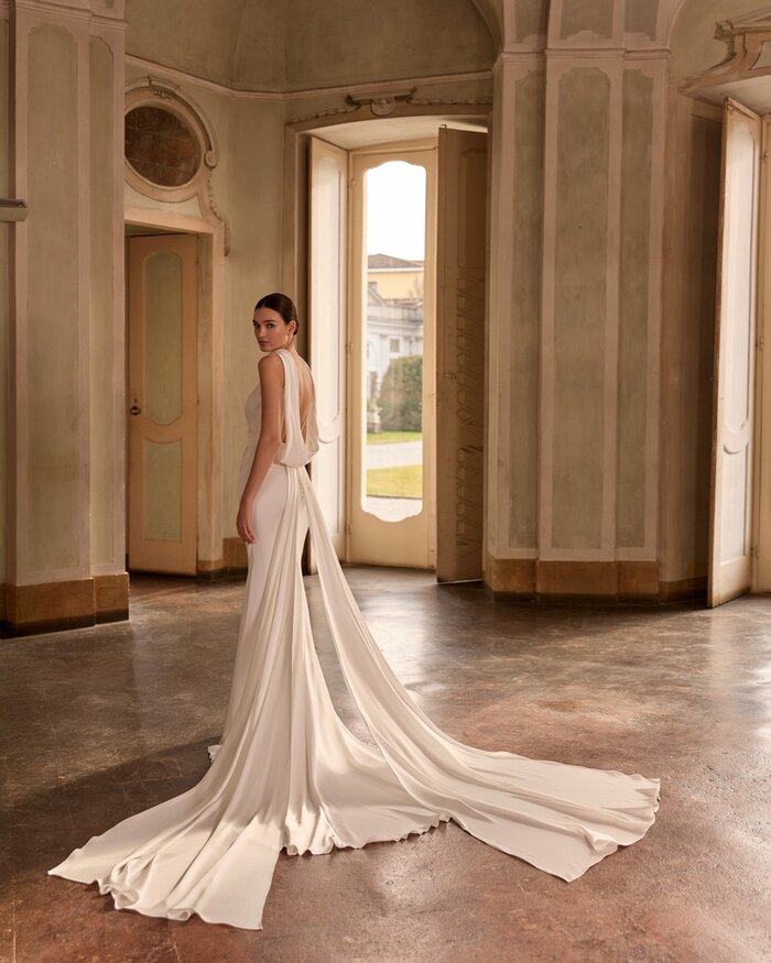 Das Brautkleid Daisy von Alberto Palatchi Brautkleid Daisy von Alberto Palatchi aus Satin mit elegantem tiefen Wasserfall-Rückenausschnitt, drapiertem Oberteil, figurbetontem Fit-and-Flare-Schnitt und fließender langer Schleppe