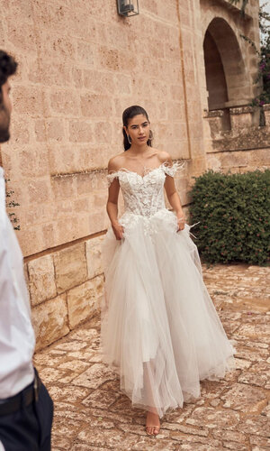 Das Brautkleid Merysol von Modeca Das Brautkleid Merysol von Modeca mit Tüllrock mit einem Perlen verzierten Spitzenoberteil und Federn