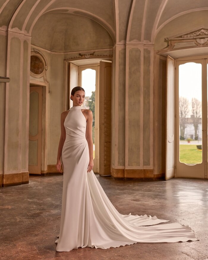 Das Brautkleid Daisy von Alberto Palatchi Brautkleid Daisy von Alberto Palatchi aus Satin mit elegantem tiefen Wasserfall-Rückenausschnitt, drapiertem Oberteil, figurbetontem Fit-and-Flare-Schnitt und fließender langer Schleppe