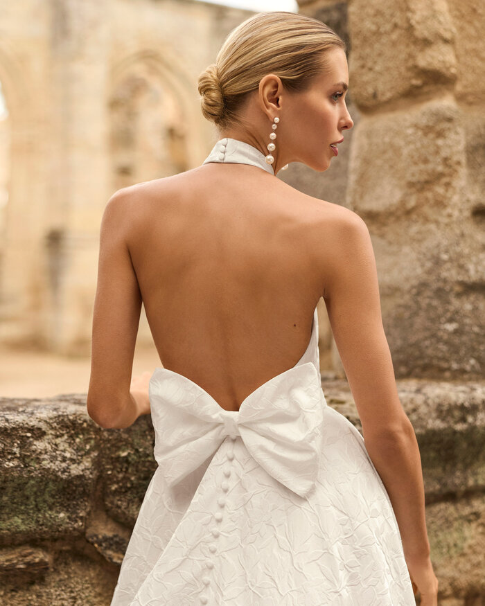 Das Brautkleid Prado von Adriana Alier Brautkleid Prado von Adriana Alier mit elegantem Neckholder-Ausschnitt, floraler Jacquard-Struktur in der Rückenansicht