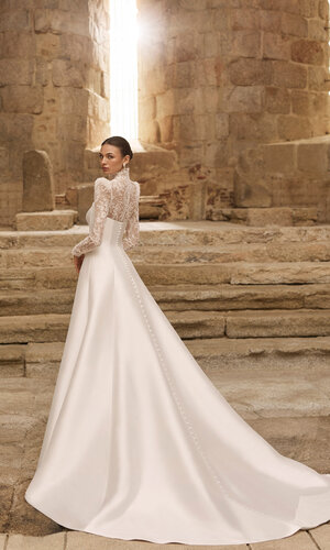 Das Brautkleid Pomelo von Adriana Alier Elegantes weißes Brautkleid in der Rückenansicht mit Off-Shoulder-Ausschnitt und fließendem ausgestelltem Rock