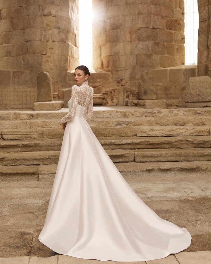Das Brautkleid Pomelo von Adriana Alier Elegantes weißes Brautkleid in der Rückenansicht mit Off-Shoulder-Ausschnitt und fließendem ausgestelltem Rock
