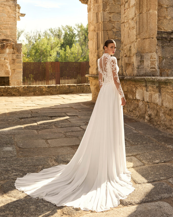 Das Brautkleid Papiro von Adriana Alier Brautkleid Papiro von Adriana Alier mit floraler Spitze, tiefem V-Ausschnitt, feinen Trägern und fließendem Rock mit Schleppe und Spitzenjäckchen in der Rückenansicht