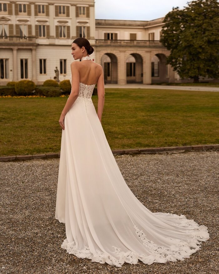 Das Brautkleid Favia von Alberto Palatchi Brautkleid Favia von Alberto Palatchi mit hochgeschlossenem floralem Spitzenoberteil mit Neckholder, taillierter Silhouette und fließendem A-Linien-Rock mit Spitzen-Schleppe