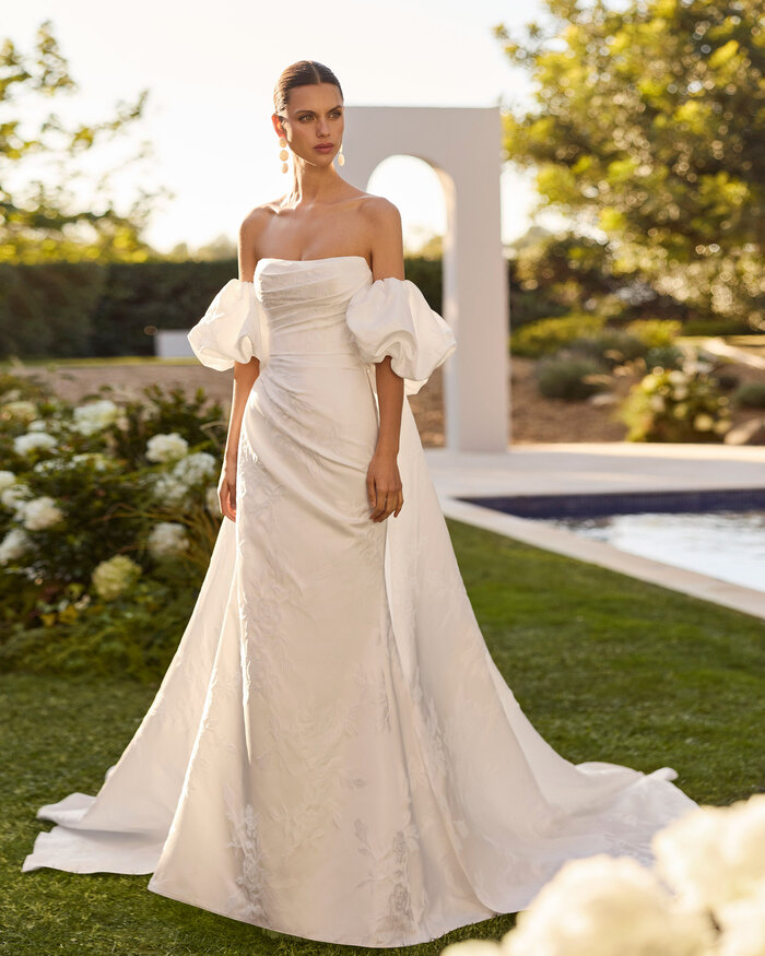 Das Brautkleid Nur von Rosa Clara Brautkleid Nur von Rosa Clará in Ivory mit elegantem schulterfreiem Ausschnitt, figurbetonter Silhouette, fließendem Rock und moderner Schleppe – hochwertiges Hochzeitskleid für stilvolle Bräute.