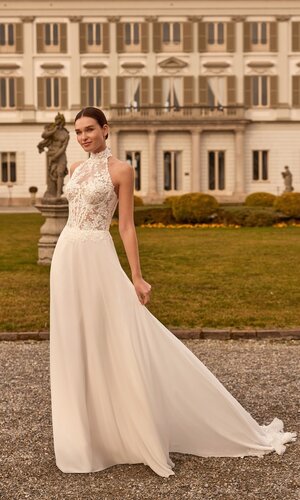 Das Brautkleid Favia von Alberto Palatchi Brautkleid Favia von Alberto Palatchi mit hochgeschlossenem floralem Spitzenoberteil mit Neckholder, taillierter Silhouette und fließendem A-Linien-Rock mit Spitzen-Schleppe