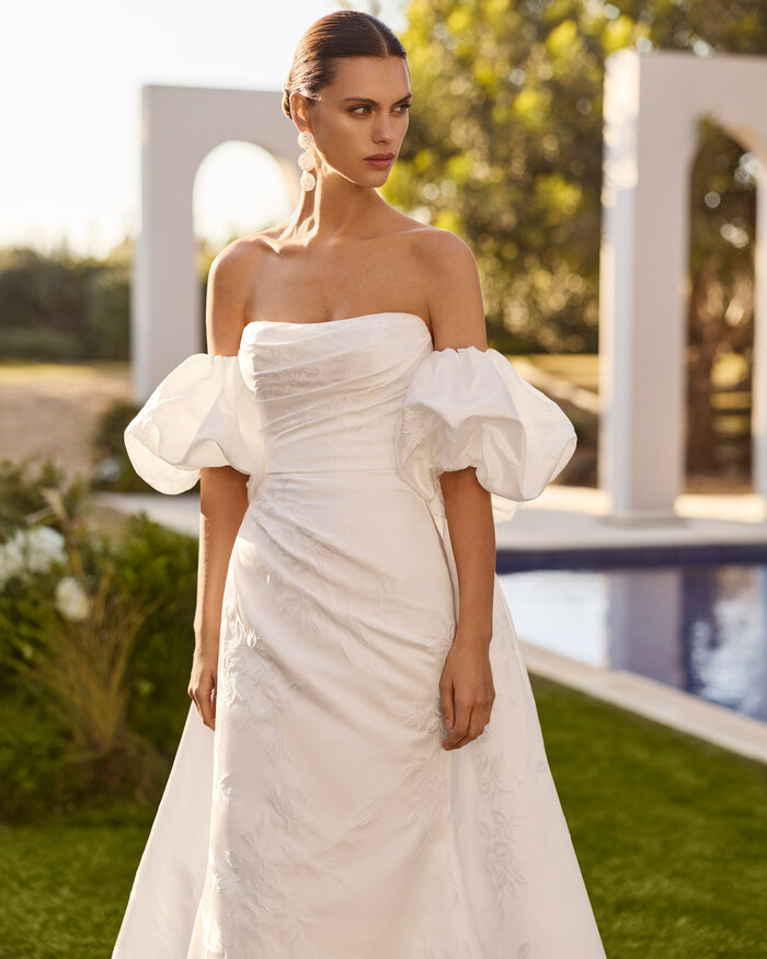 Das Brautkleid Nur von Rosa Clara Brautkleid Nur von Rosa Clará in Ivory mit elegantem schulterfreiem Ausschnitt, figurbetonter Silhouette, fließendem Rock und moderner Schleppe – hochwertiges Hochzeitskleid für stilvolle Bräute