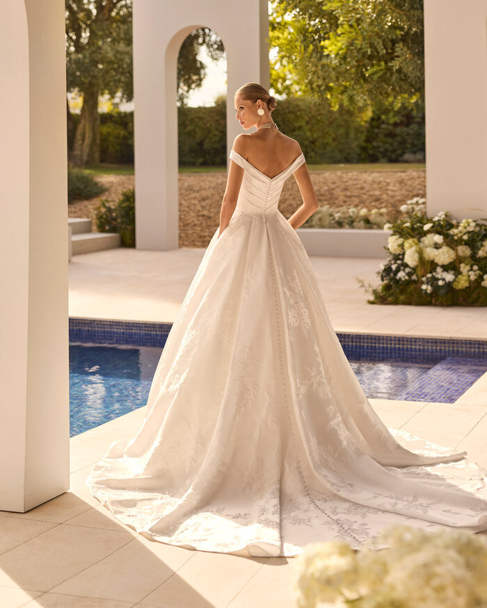 Rückenansicht Brautkleid Nupcia von Rosa Clará mit elegantem Off-Shoulder-Ausschnitt, weitem Rock und dezenter Blütenstickerei in einem Brokat Stoff