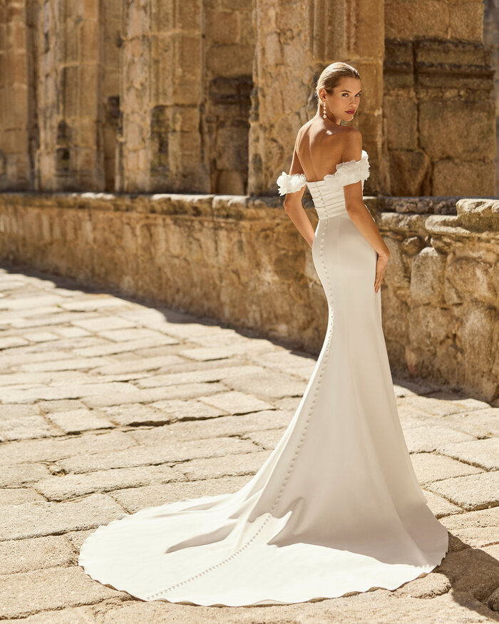 Brautkleid Paddy von Adriana Alier Rückenansicht Braut trägt das moderne Brautkleid Paddy von Adriana Alier mit trägerlosem Ausschnitt, figurbetonter Fit-and-Flare-Silhouette und langer fließender Schleppe in historischer Kulisse.