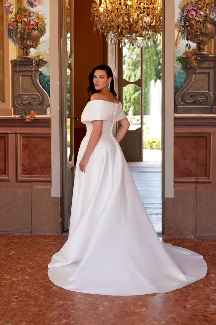 Curvy Brautkleid Harper von Justin Alexander in Ivory mit schulterfreiem Carmen-Ausschnitt, elegantem Wickeldesign, Beinschlitz und fließendem A-Linien-Rock mit schulterfreier Manschette in der Rückenansicht– modernes Plus-Size Hochzeitskleid für stilvolle Bräute 