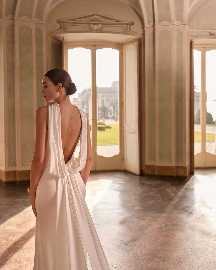 Das Brautkleid Daisy von Alberto Palatchi Brautkleid Daisy von Alberto Palatchi aus Satin mit elegantem tiefen Wasserfall-Rückenausschnitt, drapiertem Oberteil, figurbetontem Fit-and-Flare-Schnitt und fließender langer Schleppe