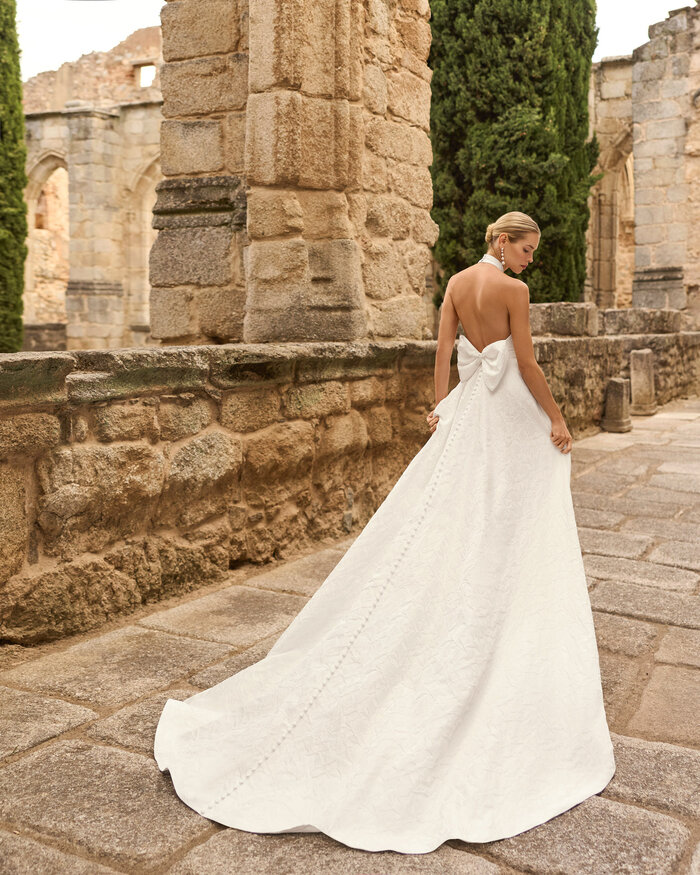 Das Brautkleid Prado von Adriana Alier Brautkleid Prado von Adriana Alier mit elegantem Neckholder-Ausschnitt, floraler Jacquard-Struktur in der Rückenansicht